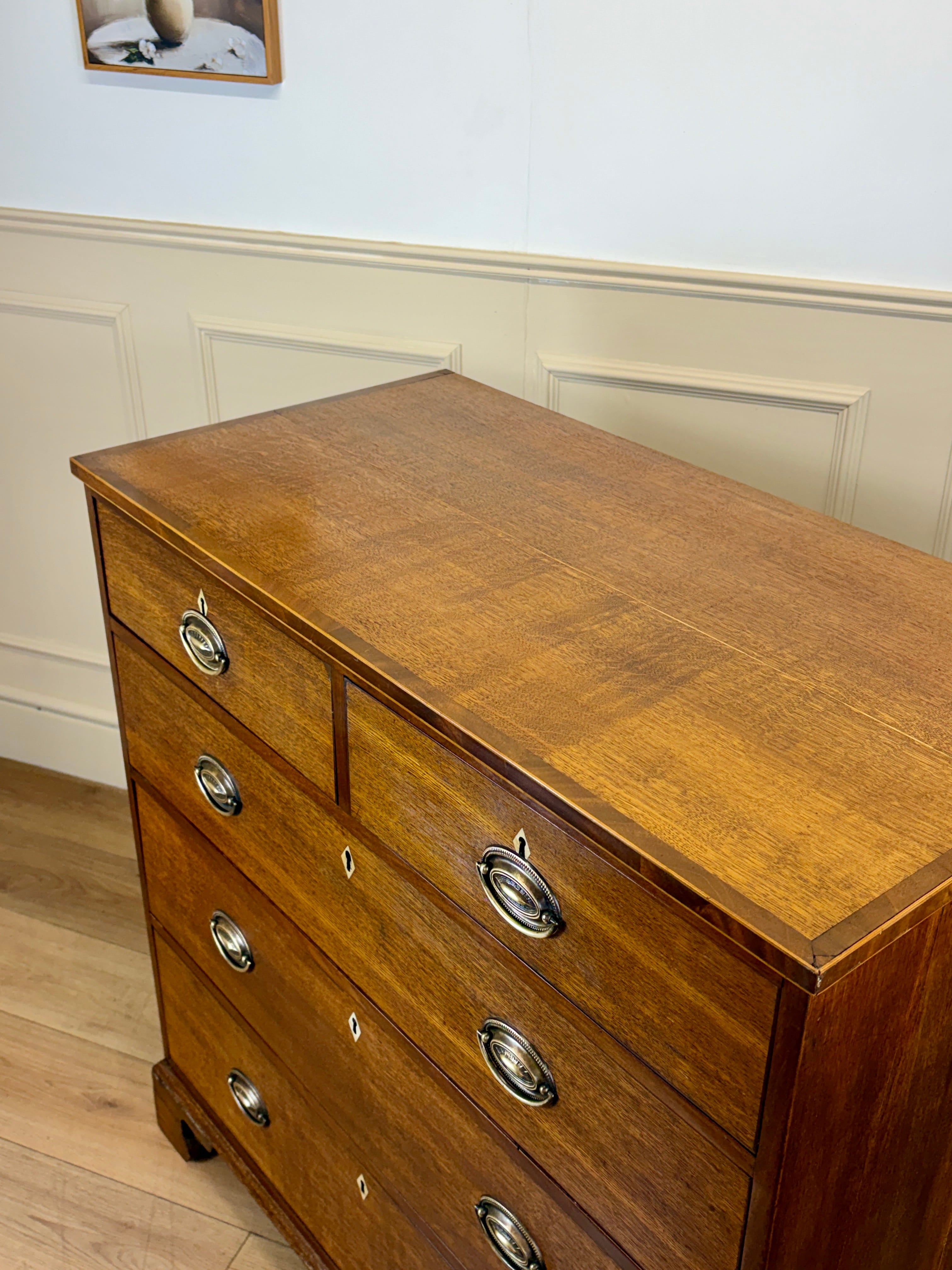Wooden dresser with metal handles in a room with white walls and wooden floor.