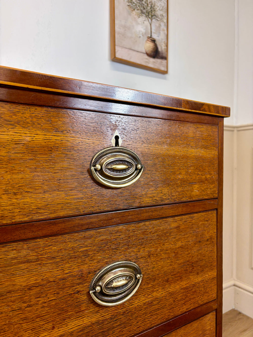 Wooden dresser with brass handles on a white wall background