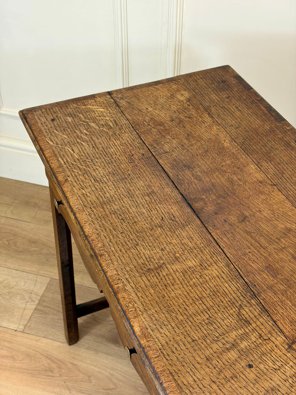 Wooden table with a rustic finish on a wooden floor.