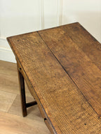 Wooden table with a rustic finish on a wooden floor.