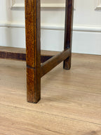 Close-up of a wooden leg on a floor with a white wall in the background