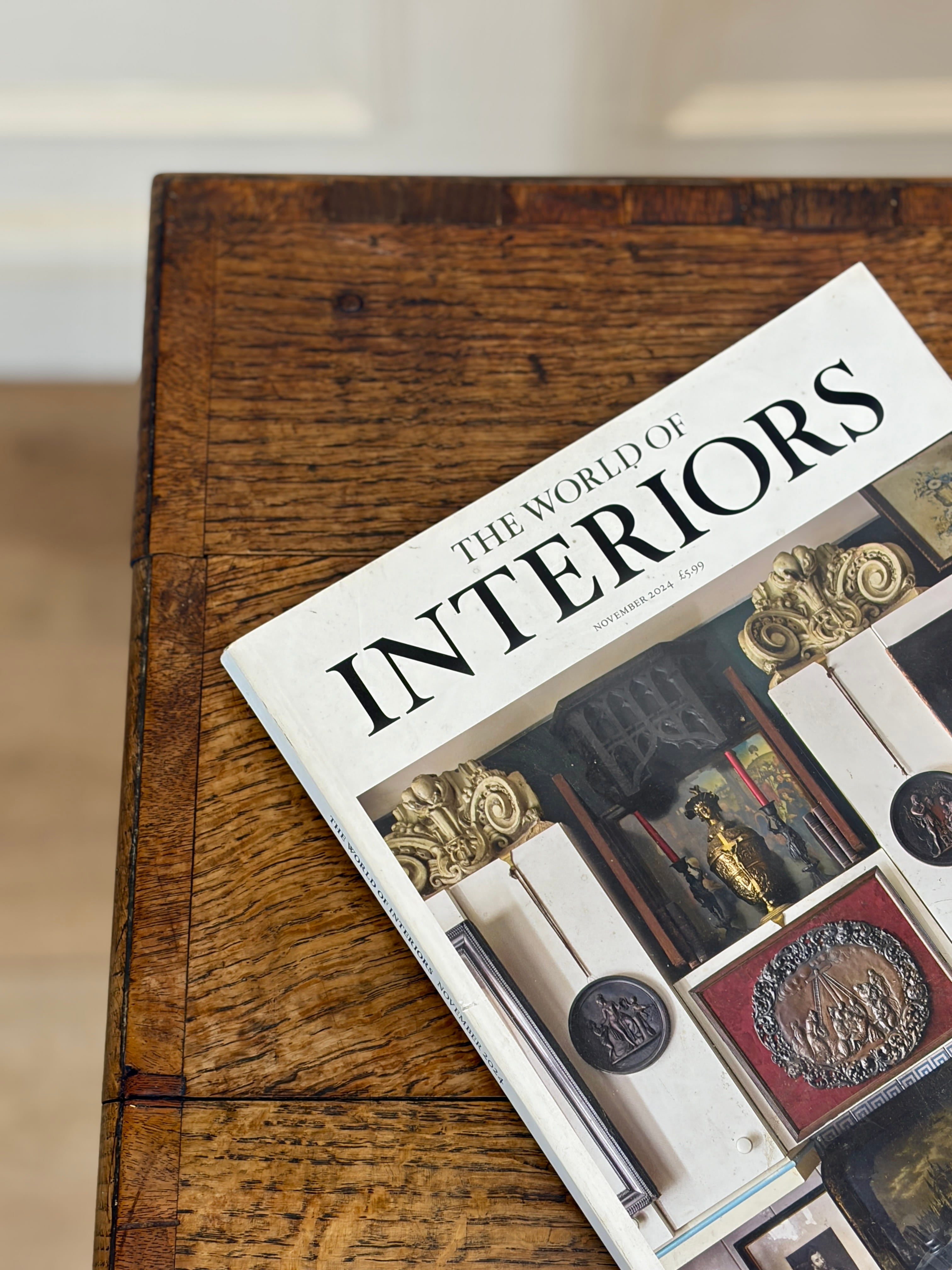 Book titled 'The World of Interiors' on a wooden surface