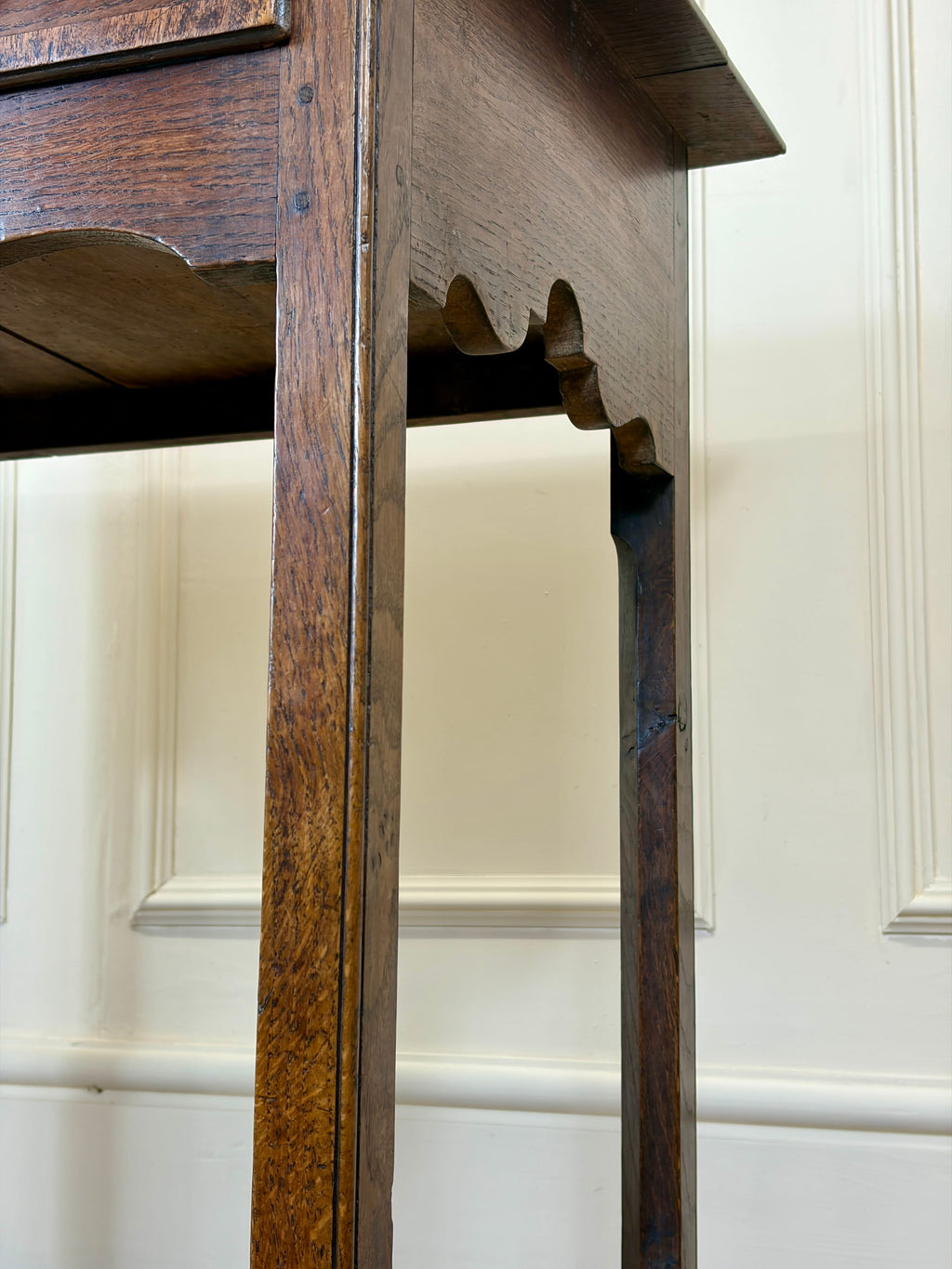 Close-up of a wooden cabinet with intricate carvings against a white paneled wall.