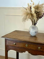 Wooden side table with a vase of dried plants on a neutral background