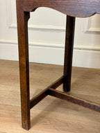 Close-up of a wooden leg on a wooden floor with a white wall background