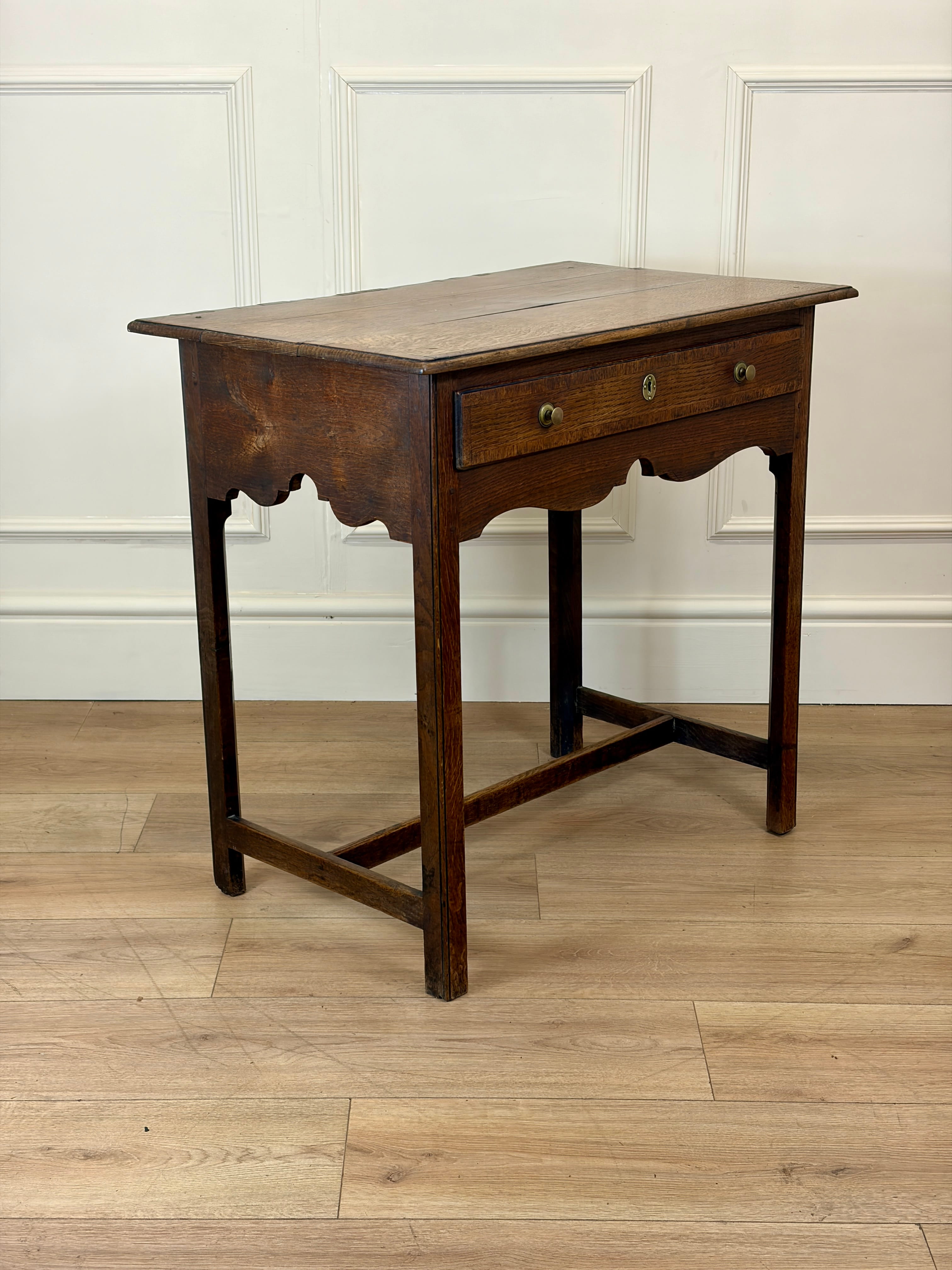 Wooden side table with a single drawer on a wooden floor.