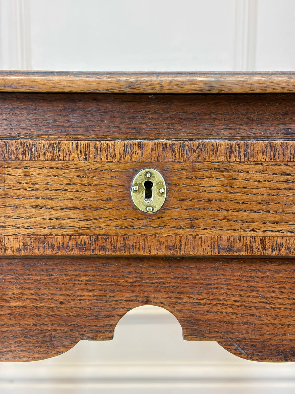 Close-up of a wooden drawer with a brass lock on a white background