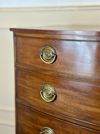 Wooden dresser with brass handles on a beige wall background