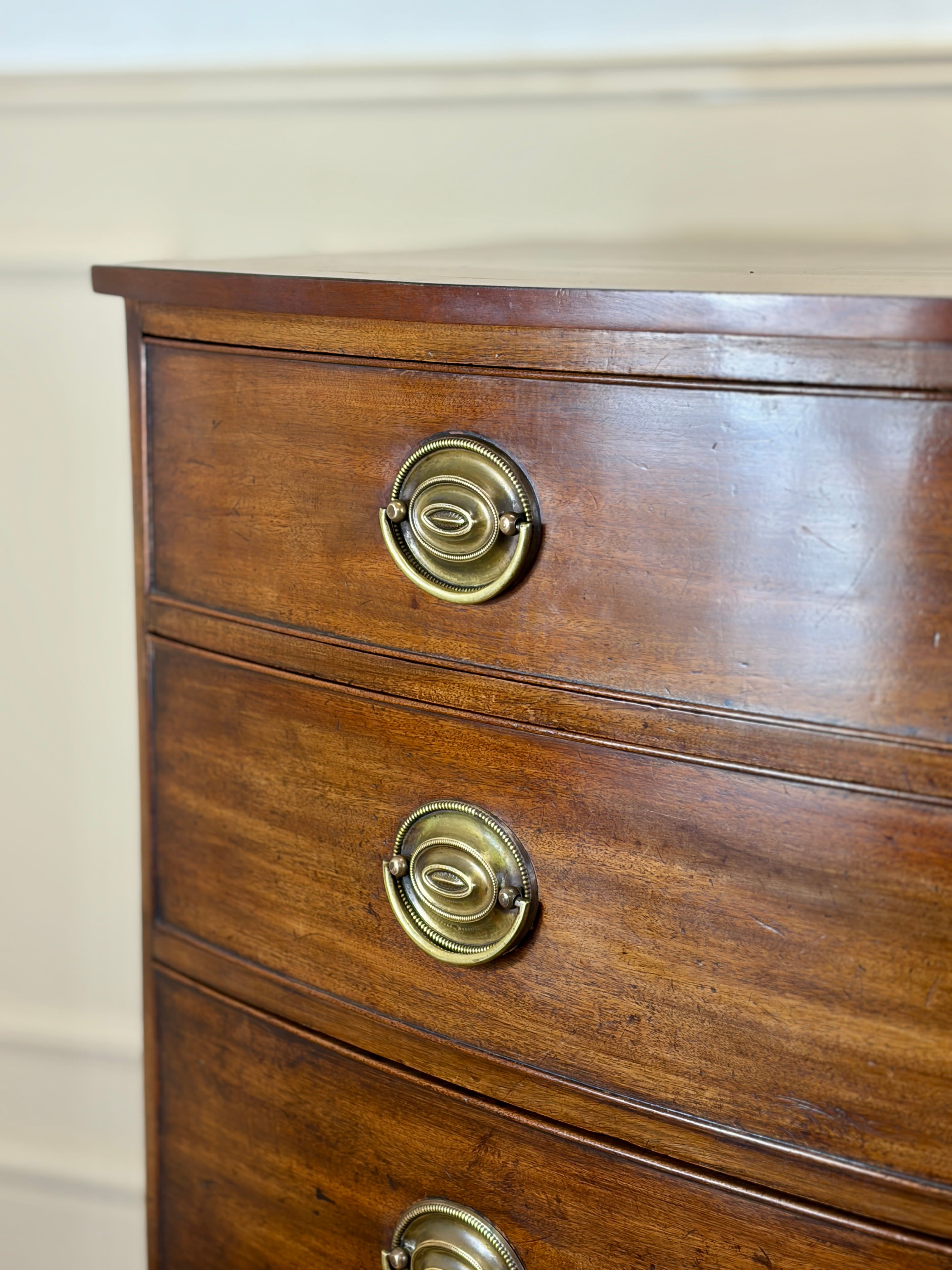 Wooden dresser with brass handles on a beige wall background