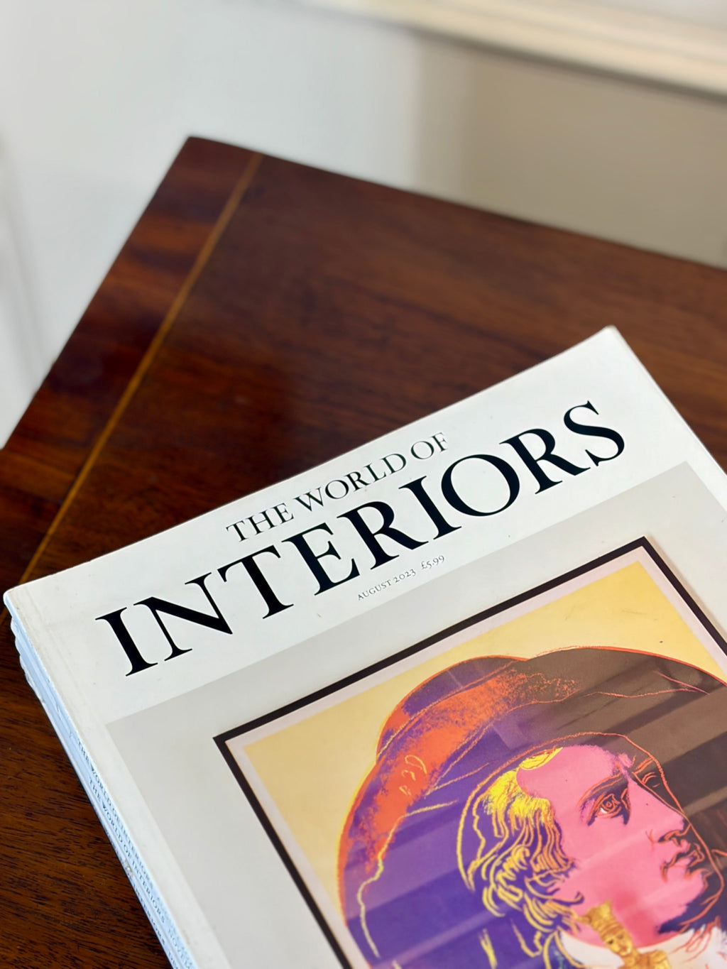 Book titled 'The World of Interiors' on a wooden surface