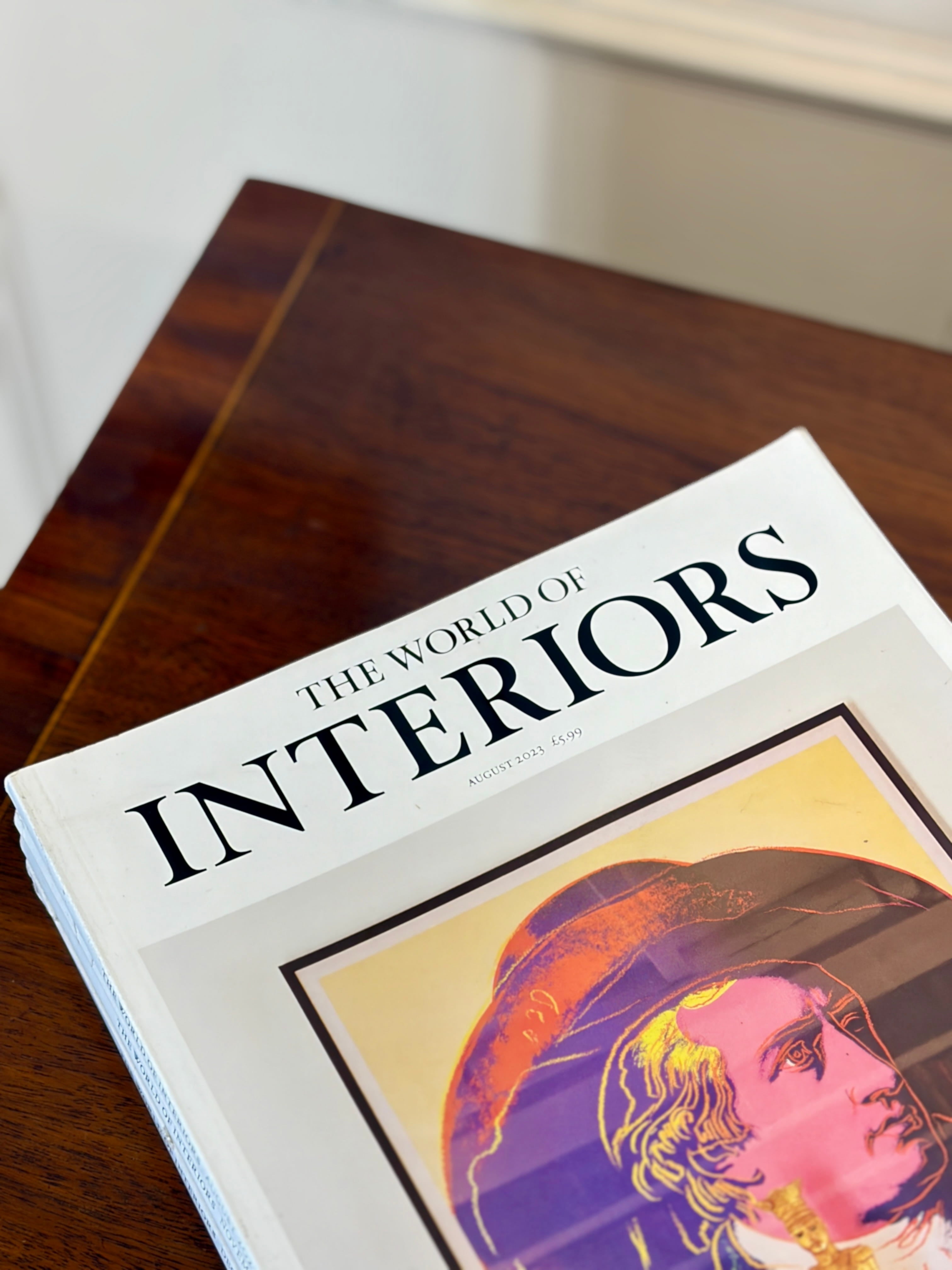 Book titled 'The World of Interiors' on a wooden surface