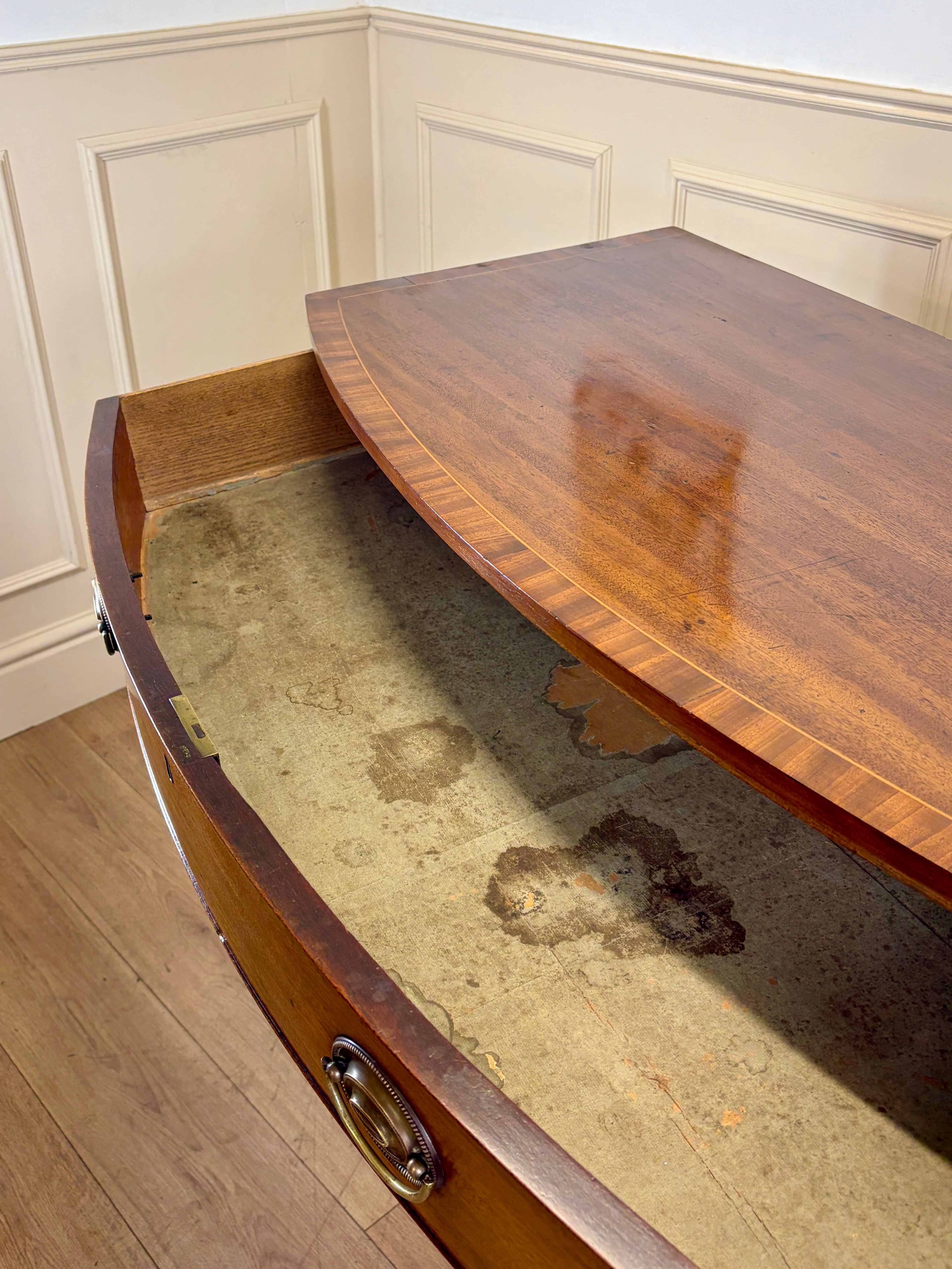 Wooden desk with glass top in a room with white paneled walls.