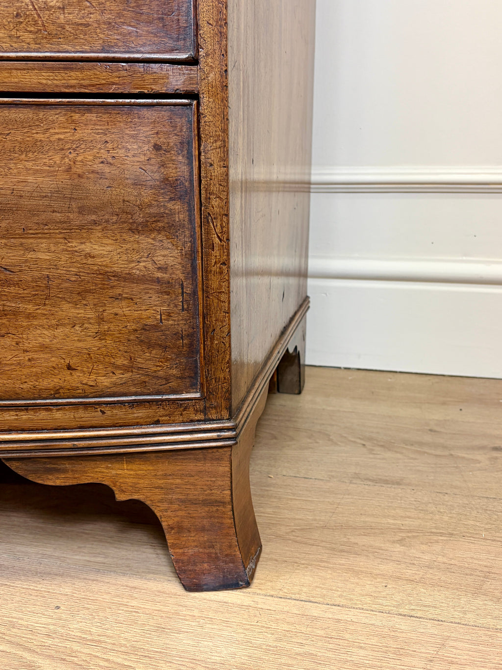 Wooden furniture leg on a wooden floor with a white wall in the background