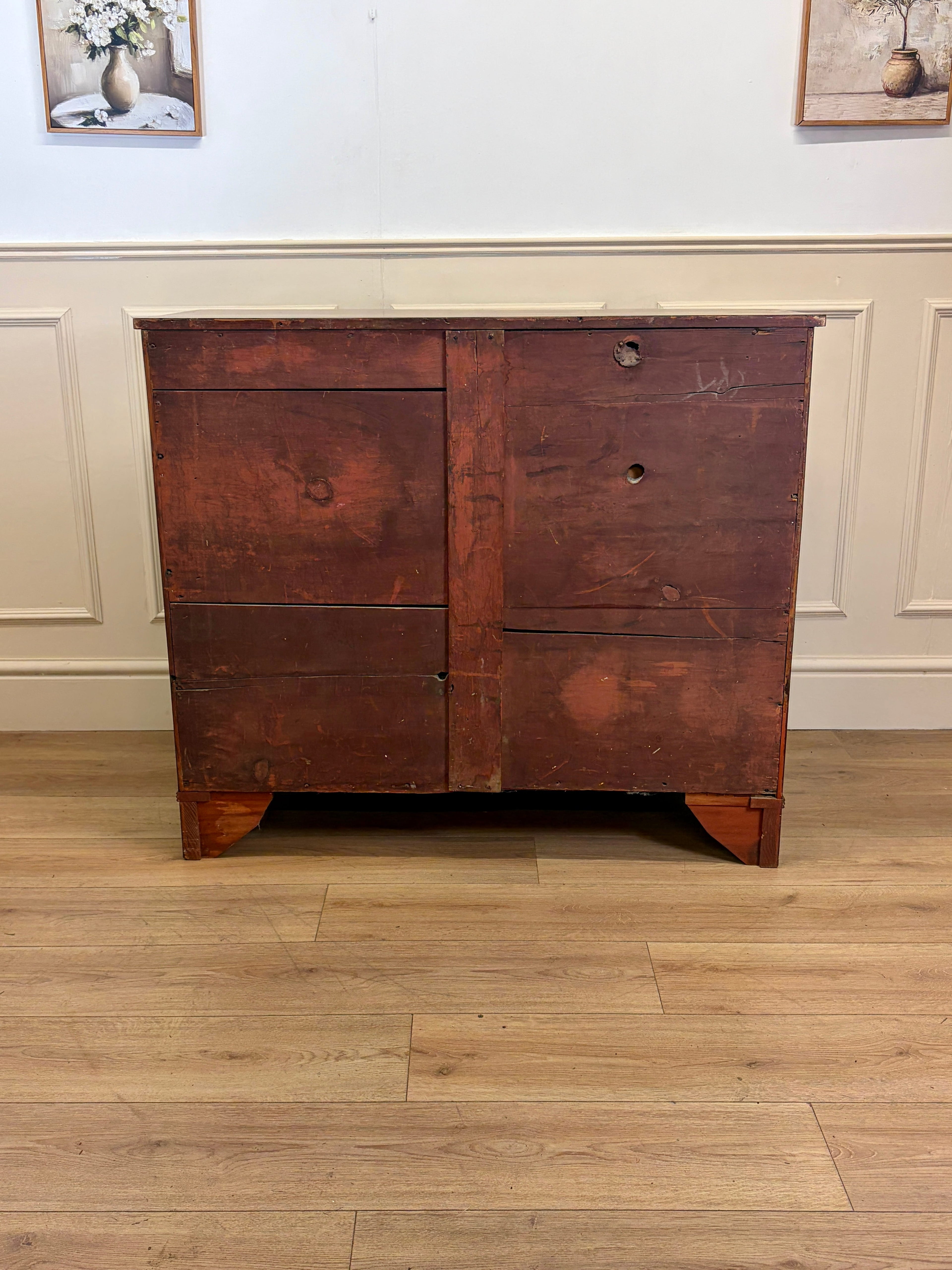 Wooden dresser with two drawers on a wooden floor against a white wall.
