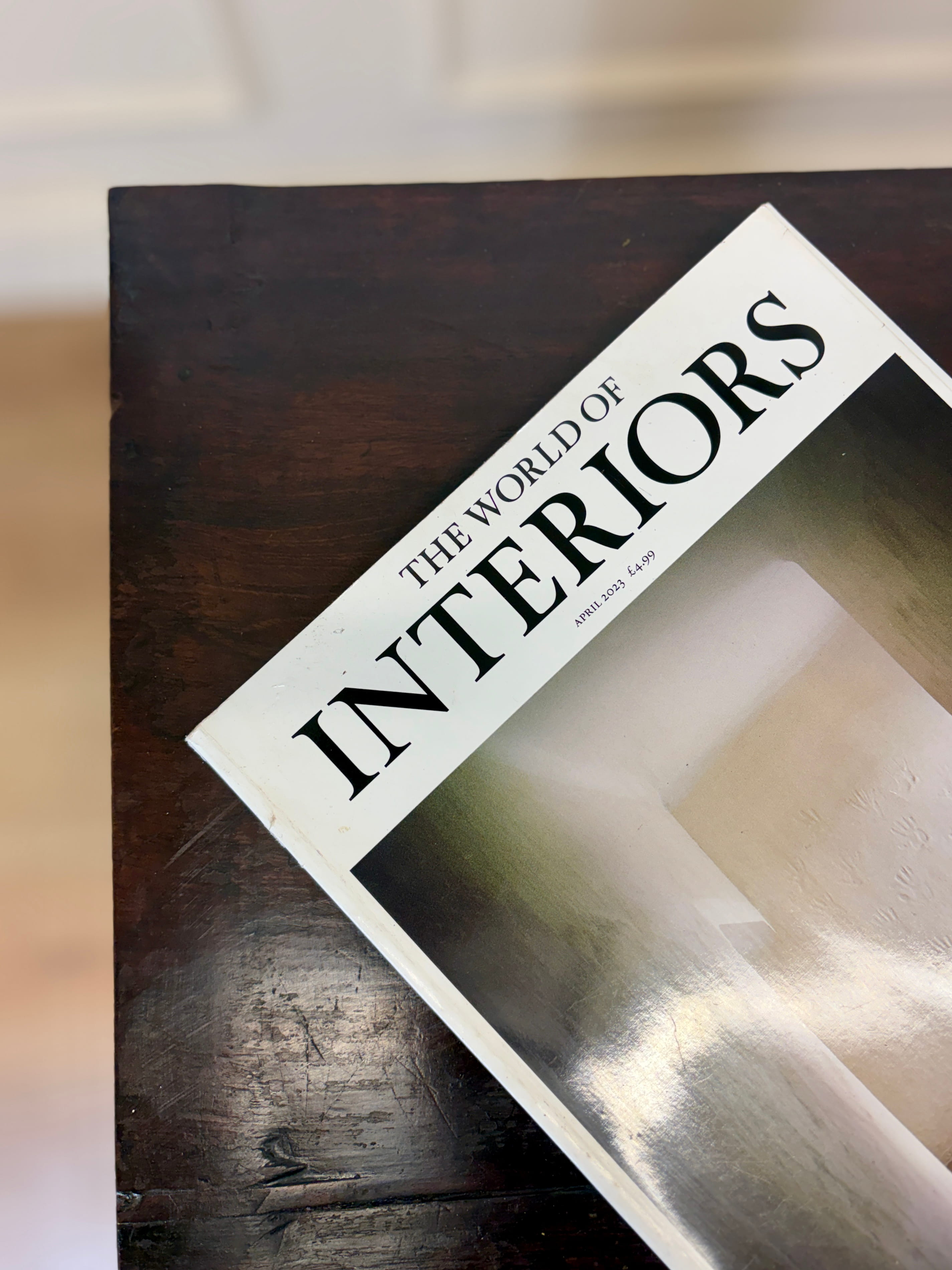 Book titled 'The World of Interiors' on a wooden surface