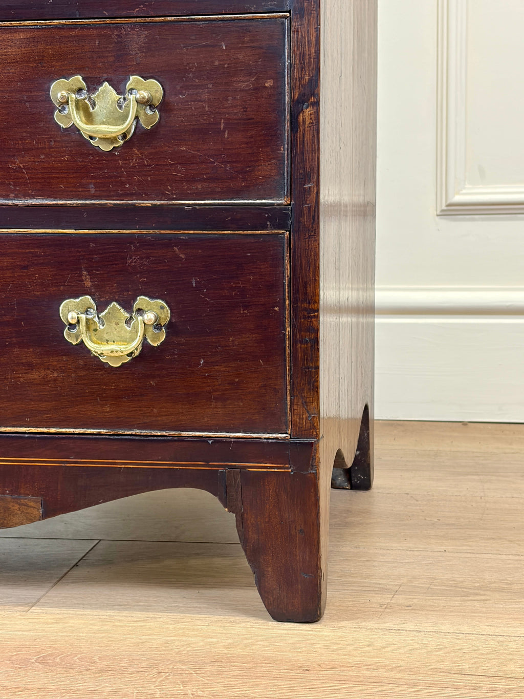 Wooden dresser with brass handles on a wooden floor.