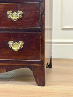 Wooden dresser with brass handles on a wooden floor.