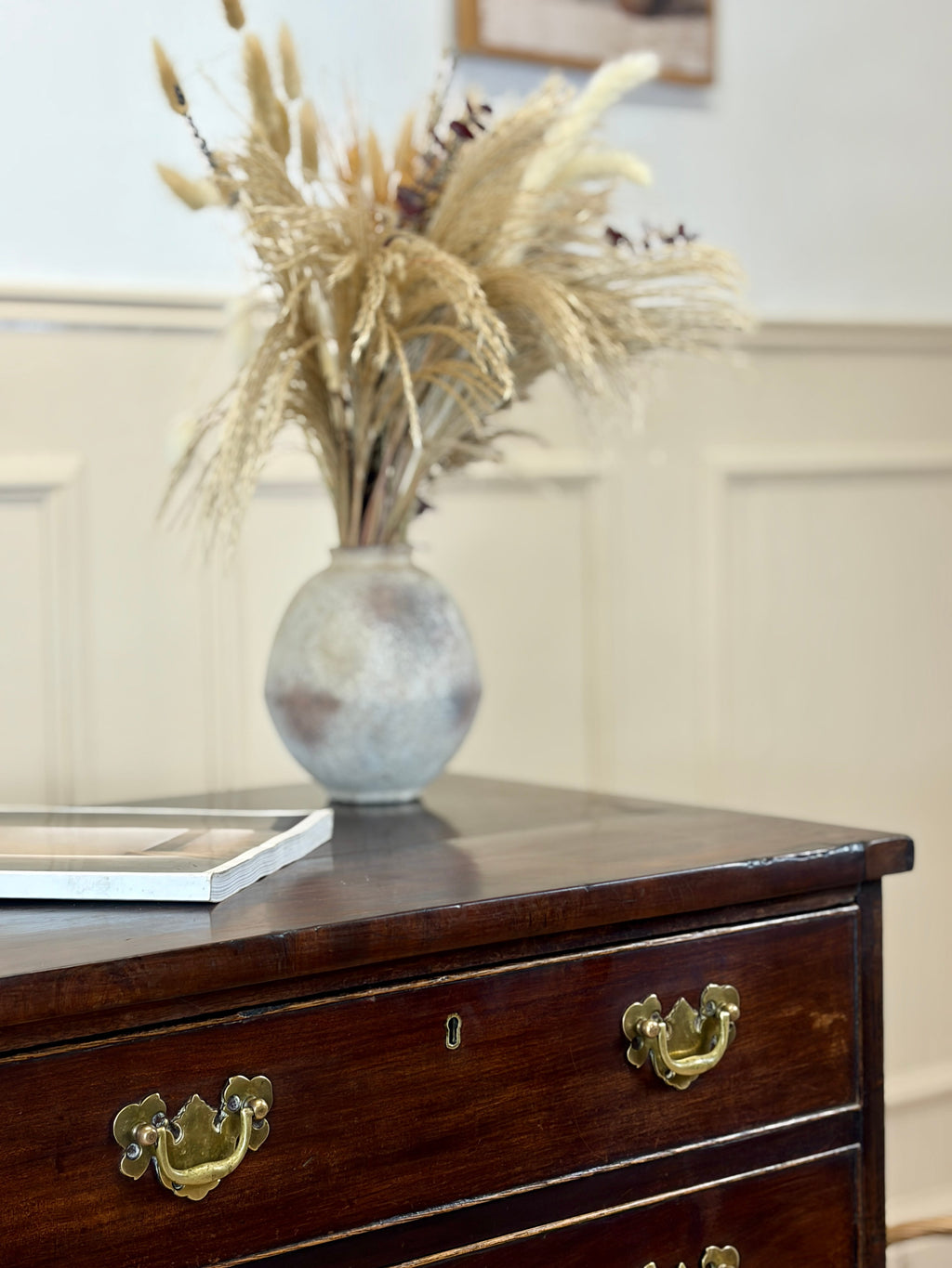 Decorative vase with dried plants on a wooden dresser