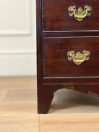Wooden dresser with brass handles on a wooden floor.
