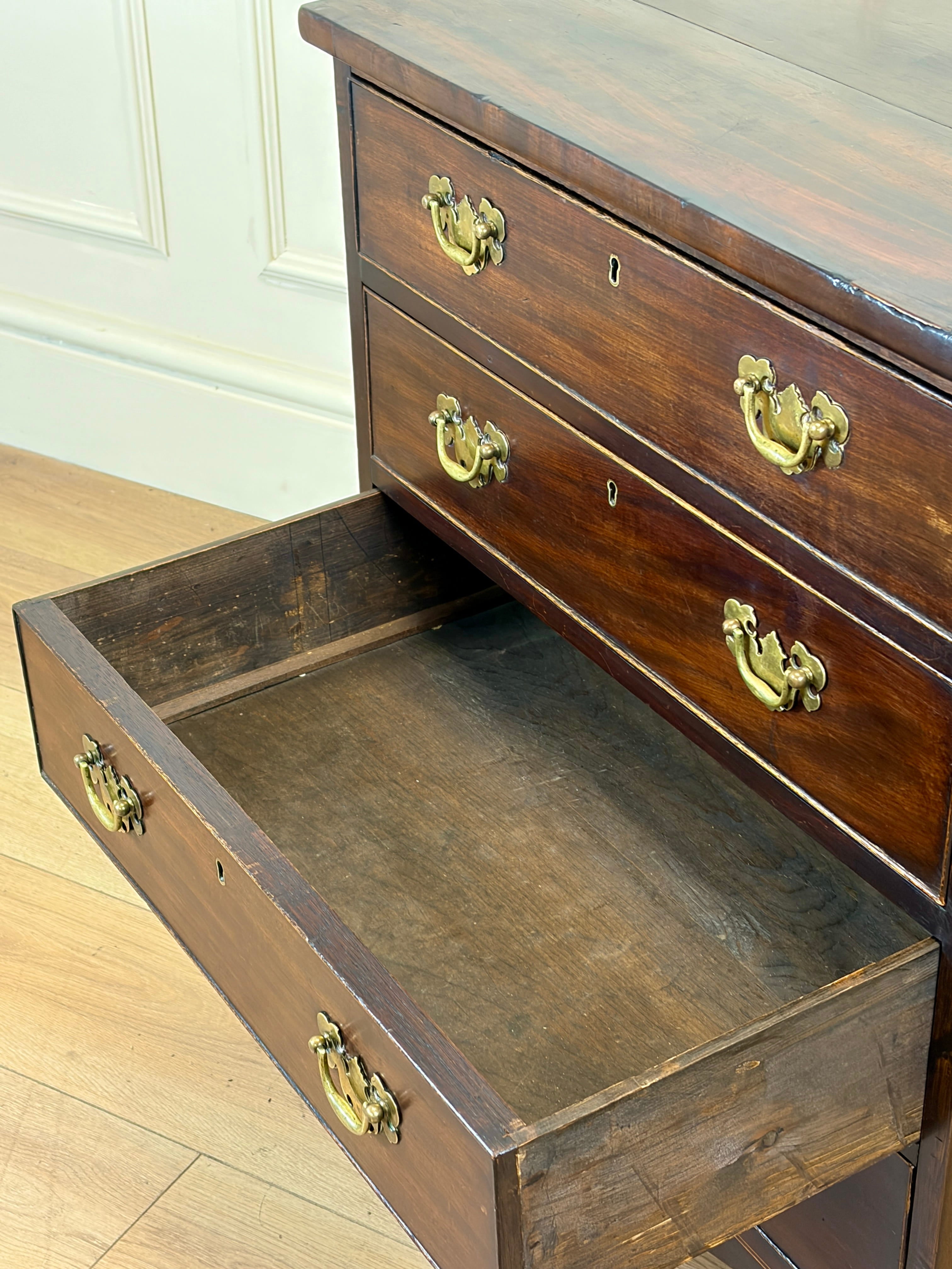 Wooden dresser with open drawer on a light wooden floor.
