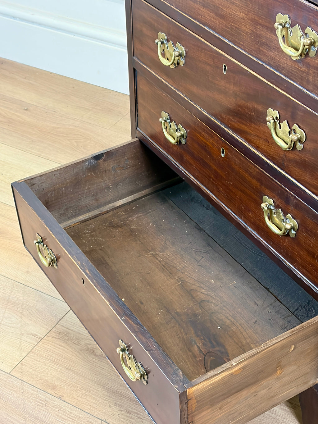 Wooden dresser with open drawer on a wooden floor