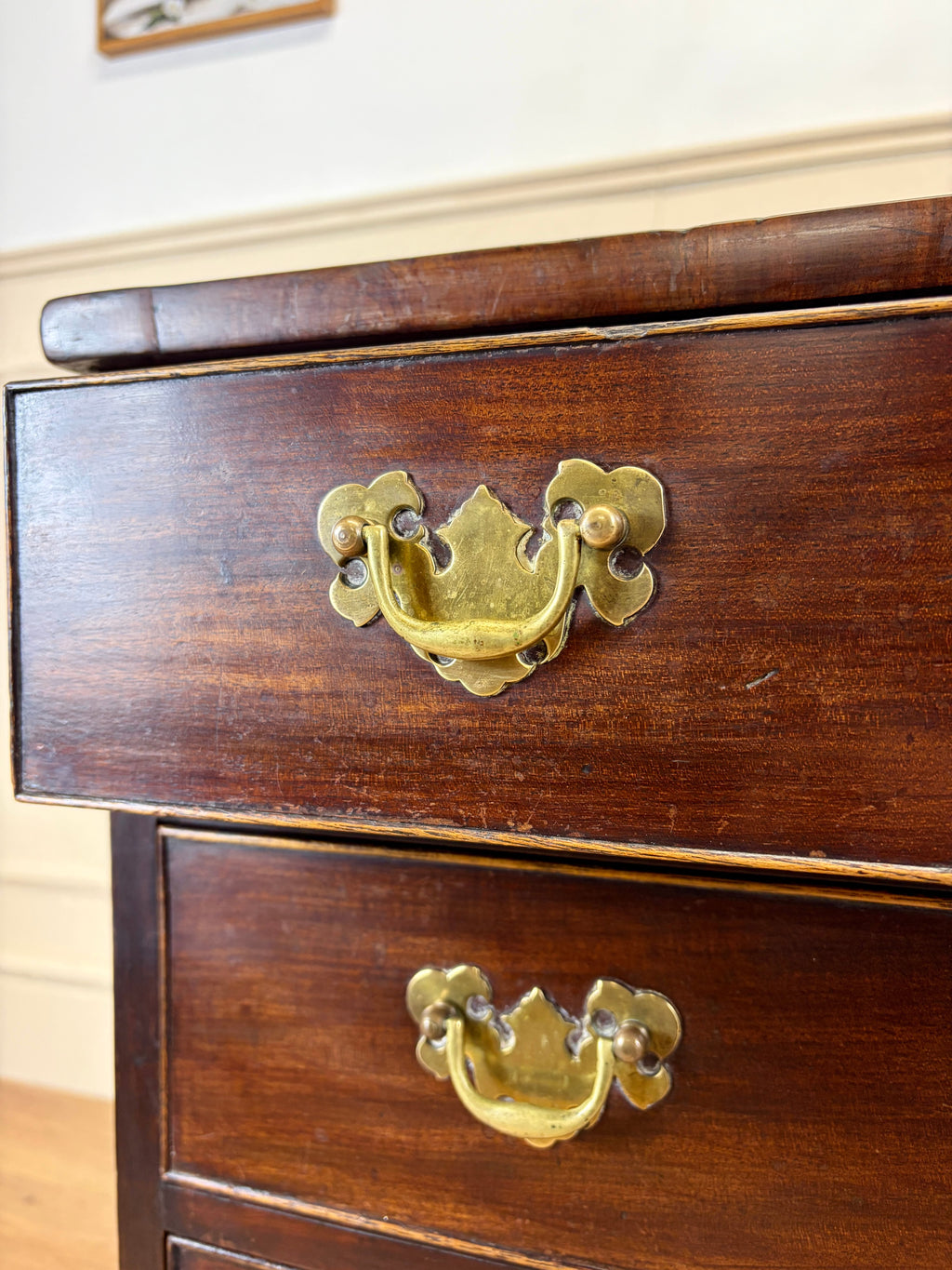 Wooden drawer with brass handles on a wooden cabinet.