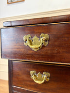 Wooden drawer with brass handles on a wooden cabinet.