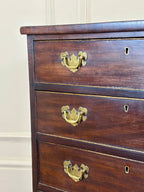 Wooden dresser with brass handles against a beige wall