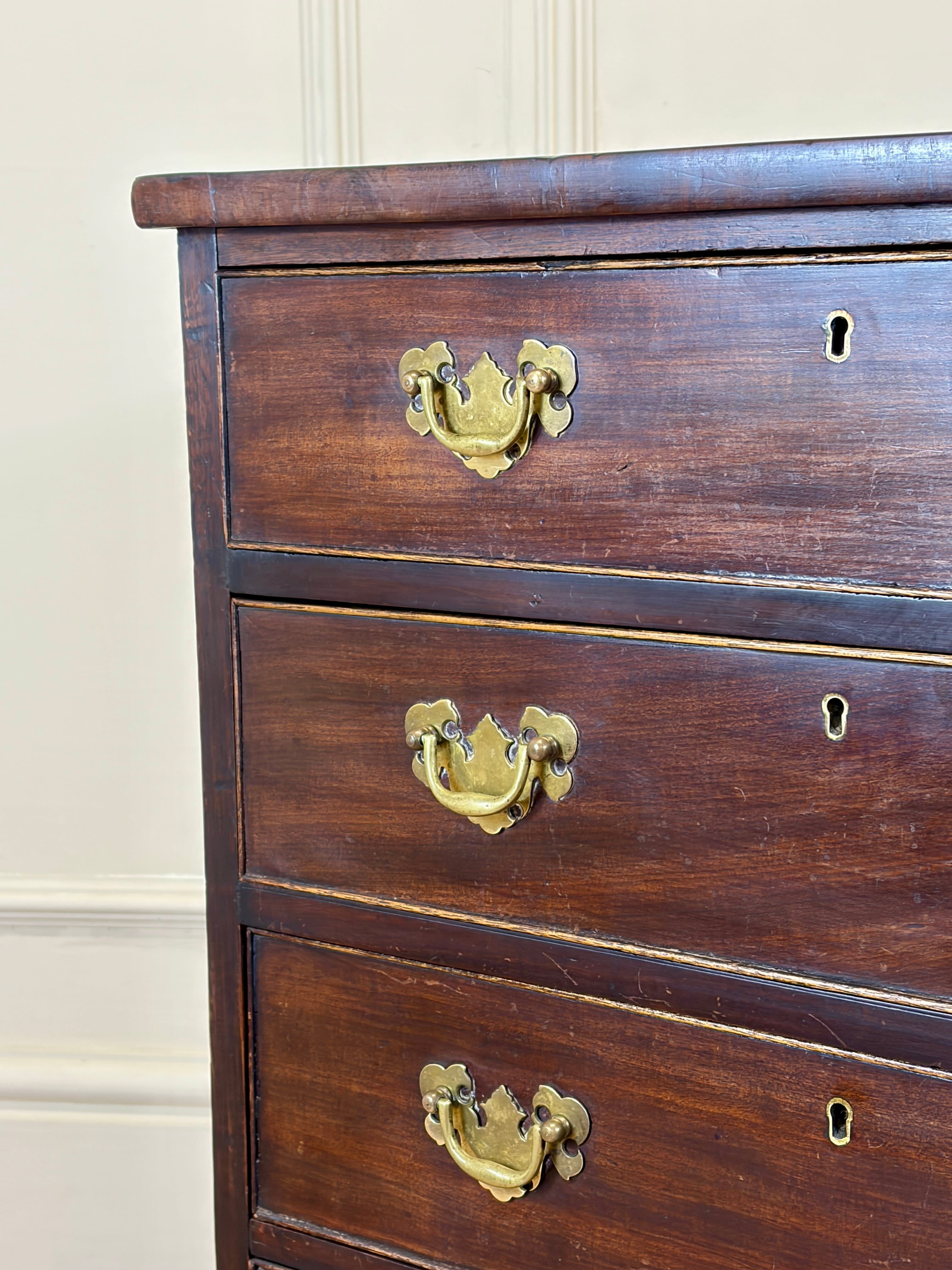 Wooden dresser with brass handles against a beige wall