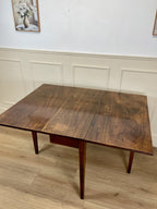 Wooden dining table in a room with light-colored walls and flooring.