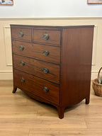 Wooden dresser with four drawers on a wooden floor.
