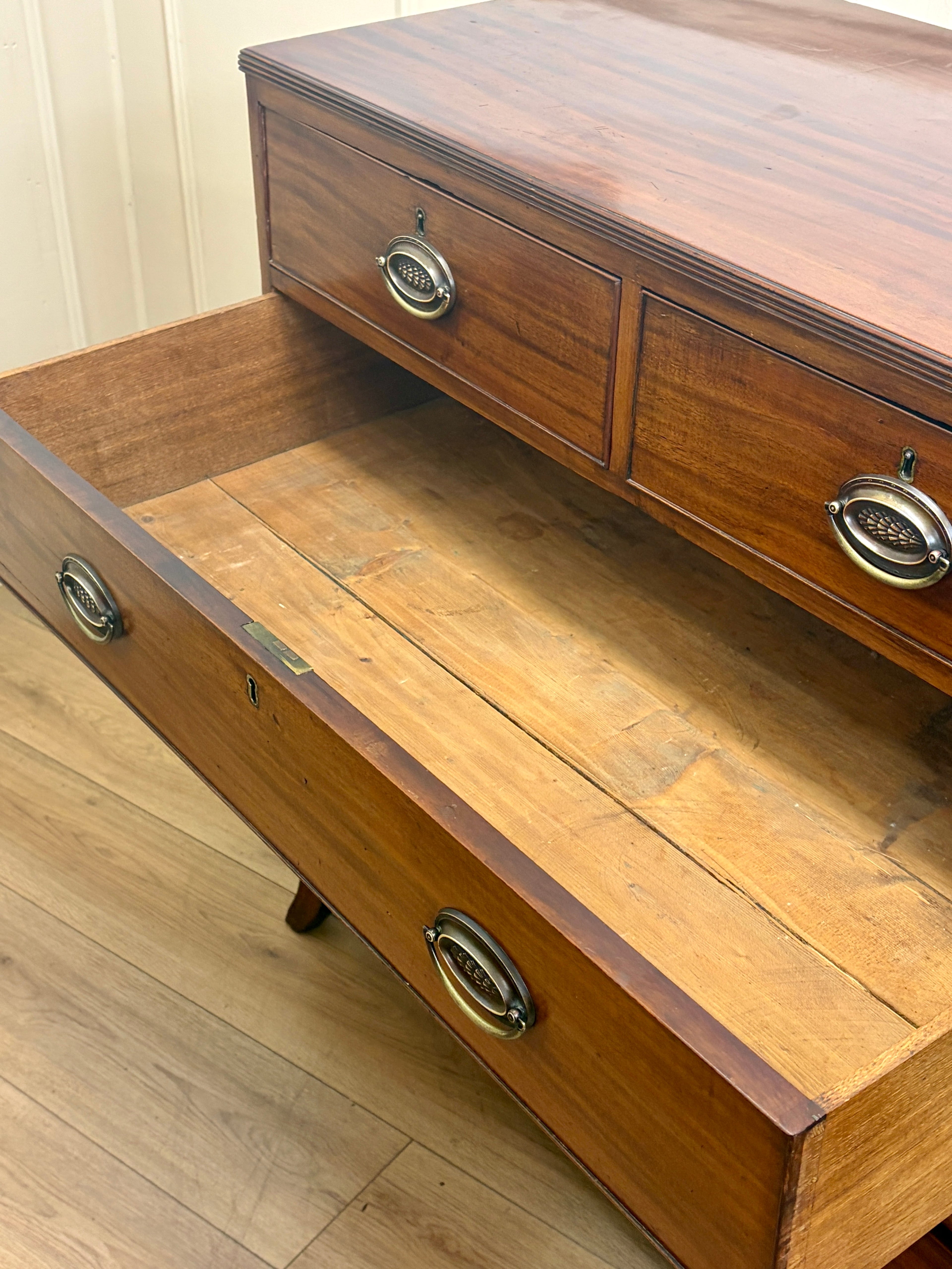 Wooden drawer unit with two visible drawers on a wooden floor.