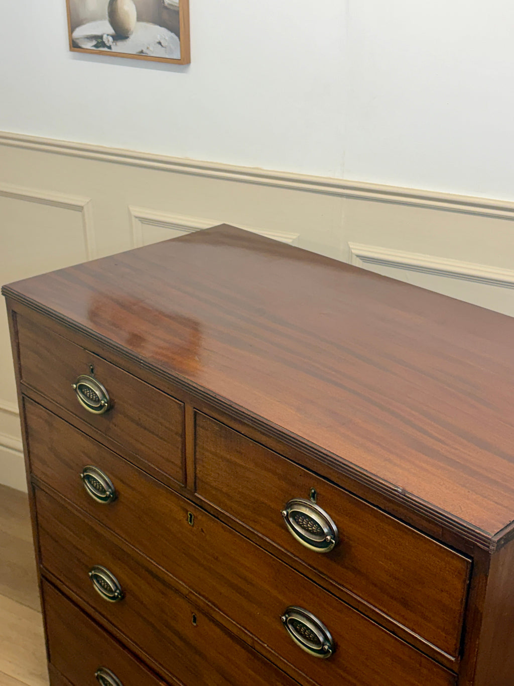 Wooden dresser with four drawers and metal handles in a room setting.