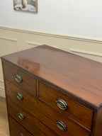 Wooden dresser with four drawers and metal handles in a room setting.