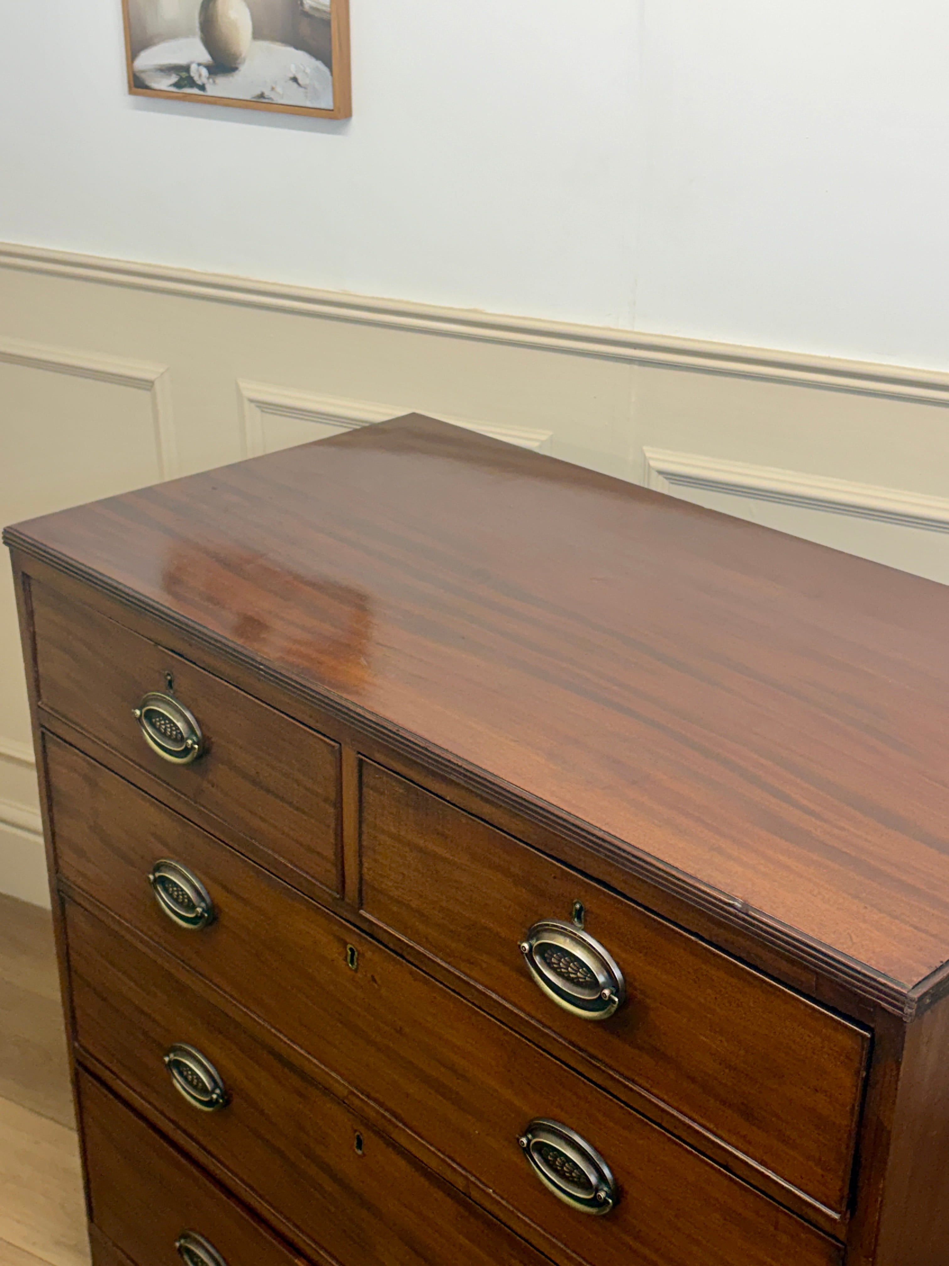 Wooden dresser with four drawers and metal handles in a room setting.