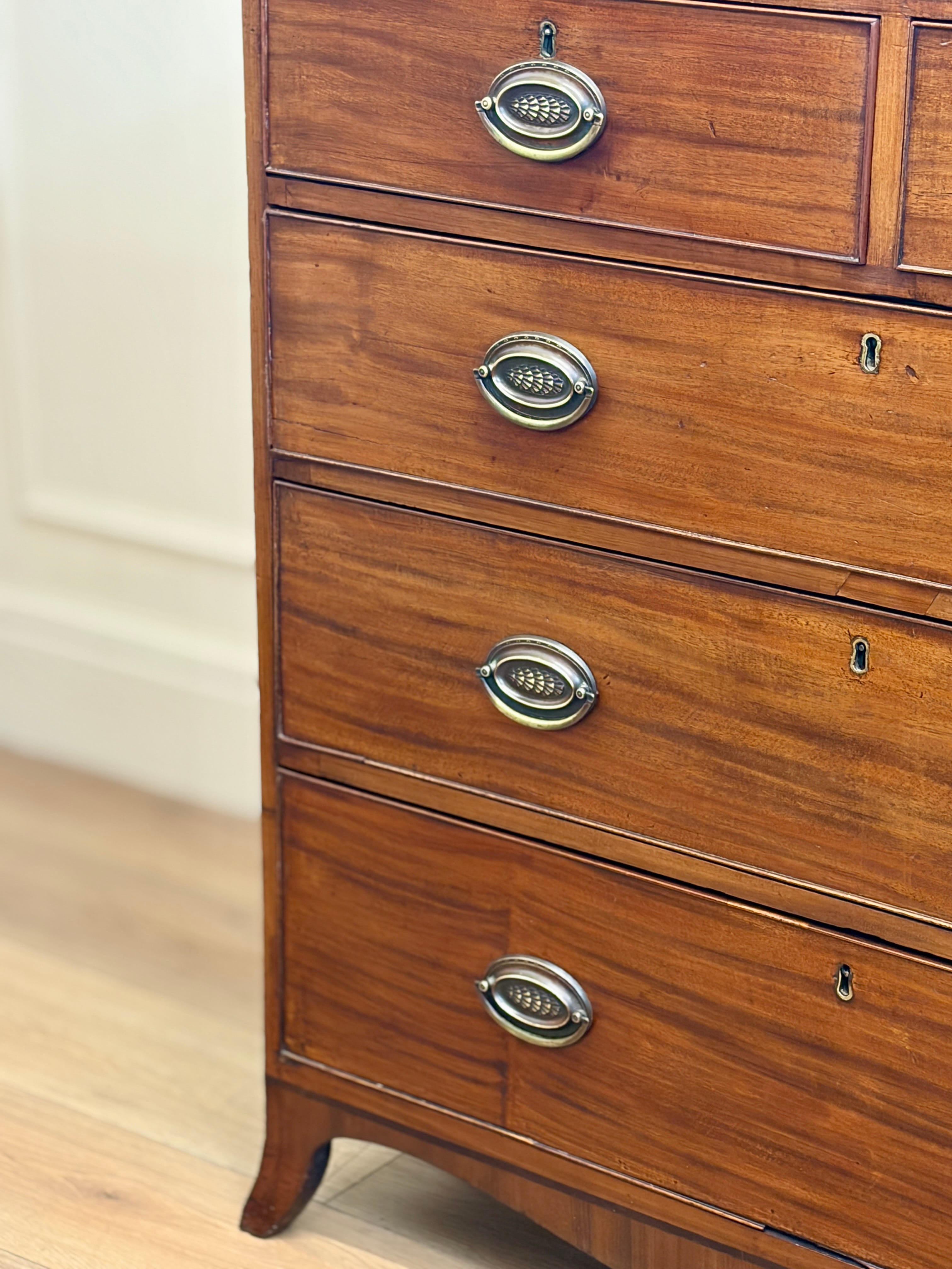 Wooden dresser with brass handles on a light wooden floor.