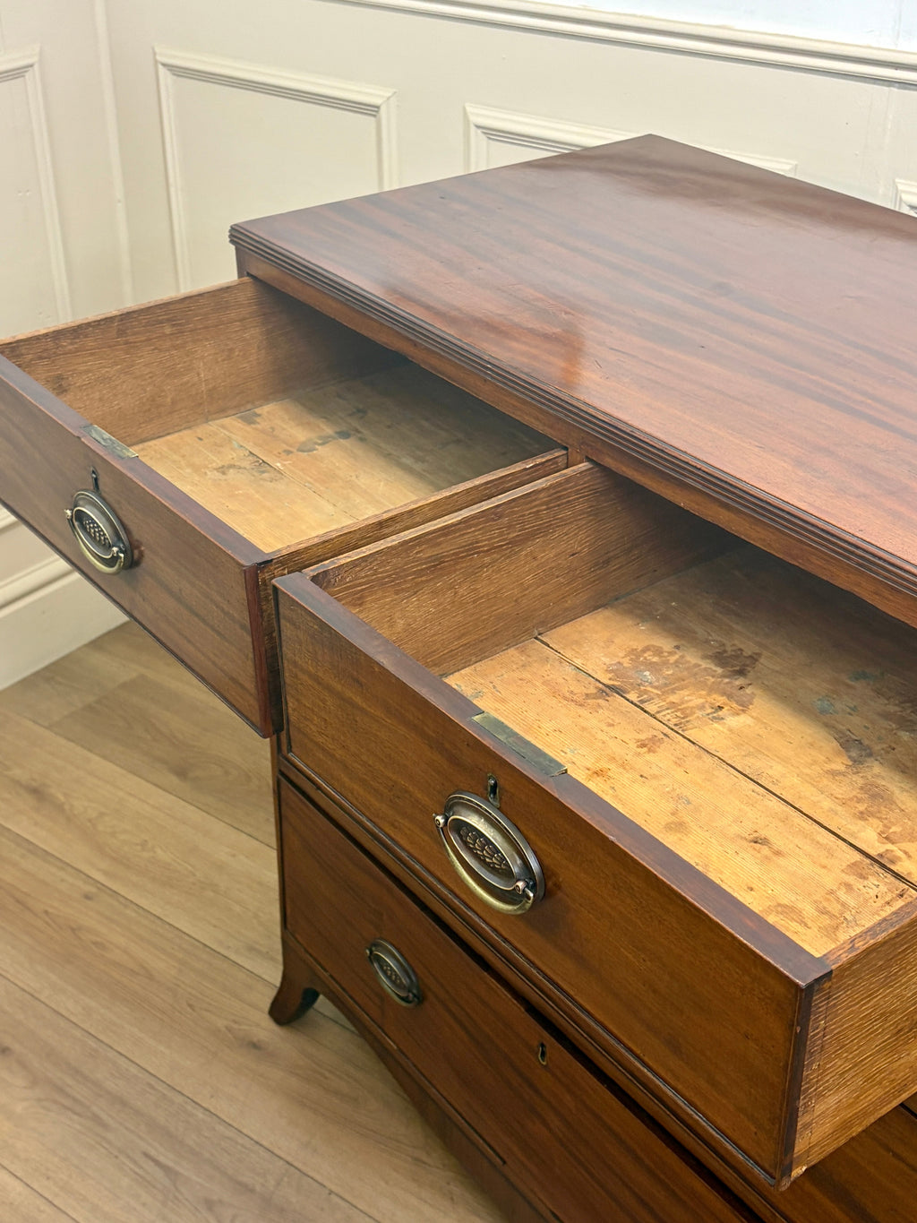 Wooden dresser with open drawers on a wooden floor.