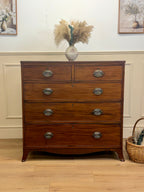 Wooden dresser with four drawers in a room with a vase of flowers on top