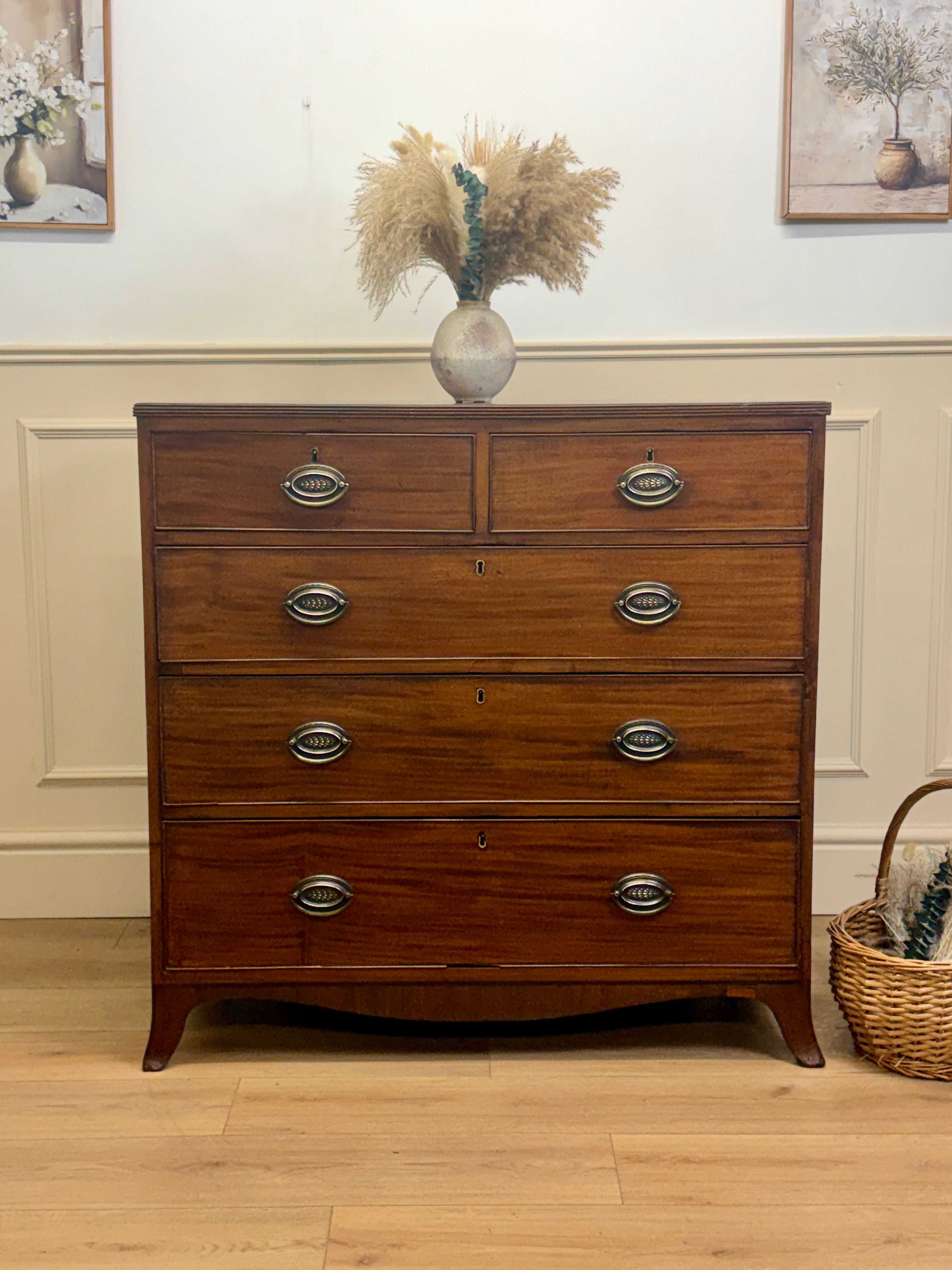Wooden dresser with four drawers in a room with a vase of flowers on top