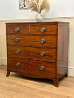Wooden dresser with silver handles on a wooden floor.