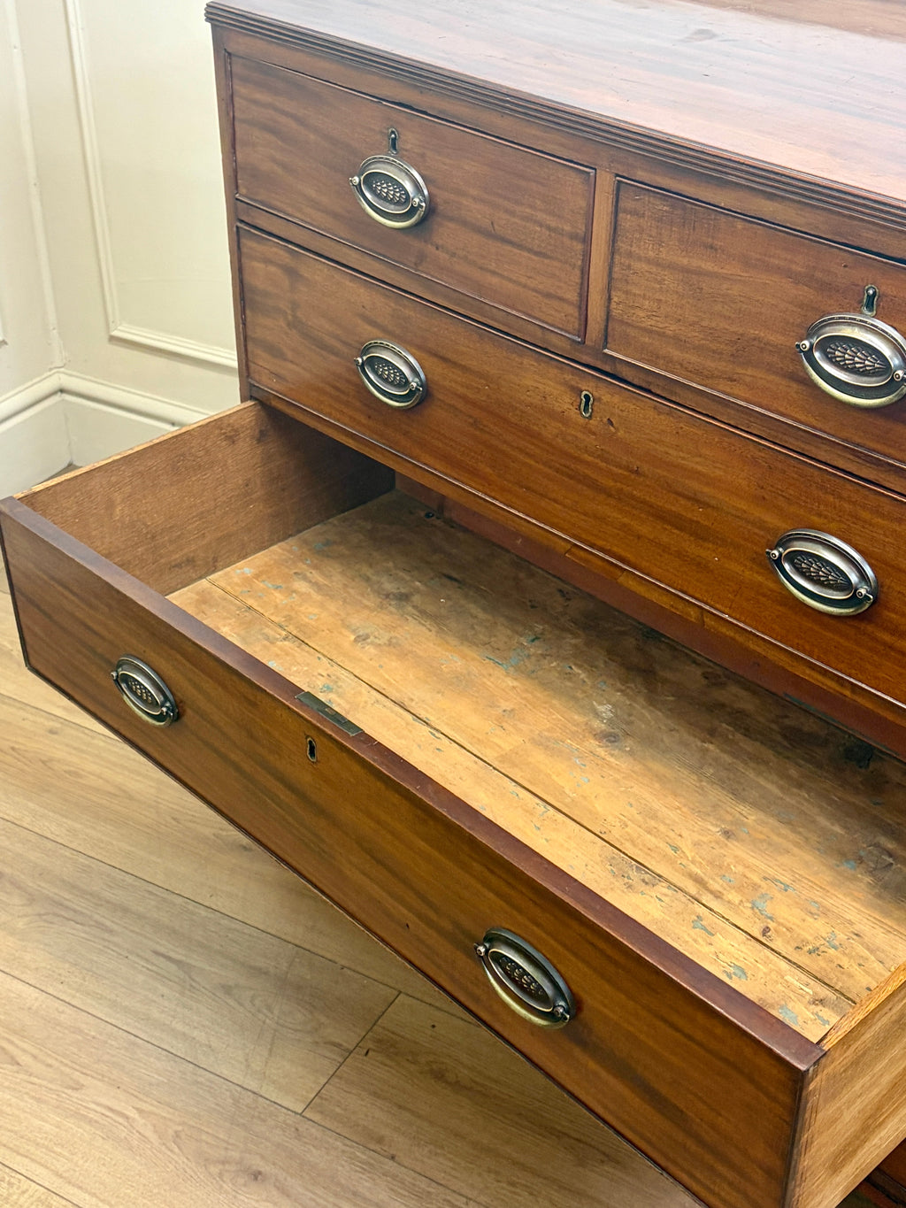 Wooden dresser with open drawer on a wooden floor