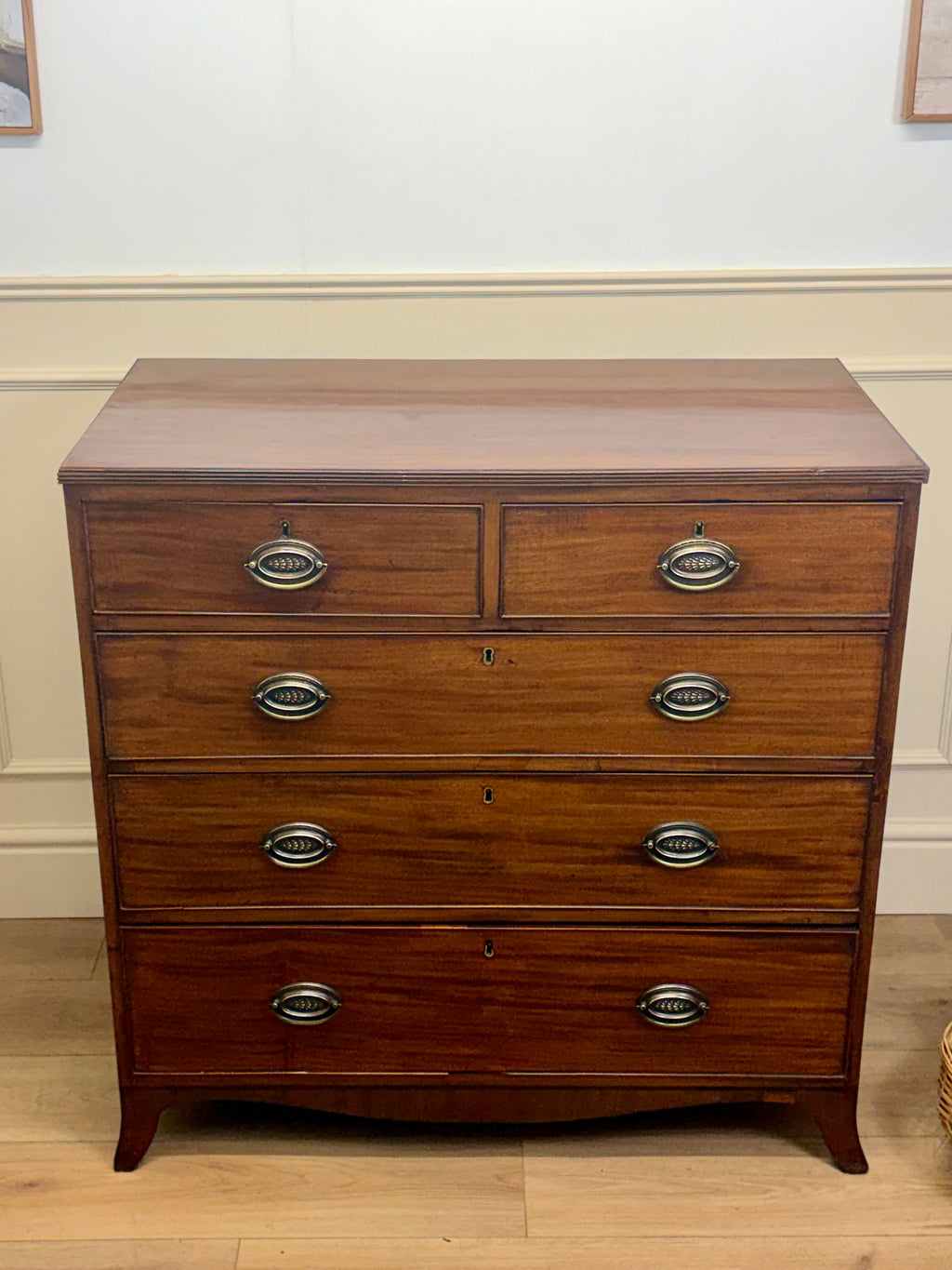 Wooden dresser with four drawers on a wooden floor.