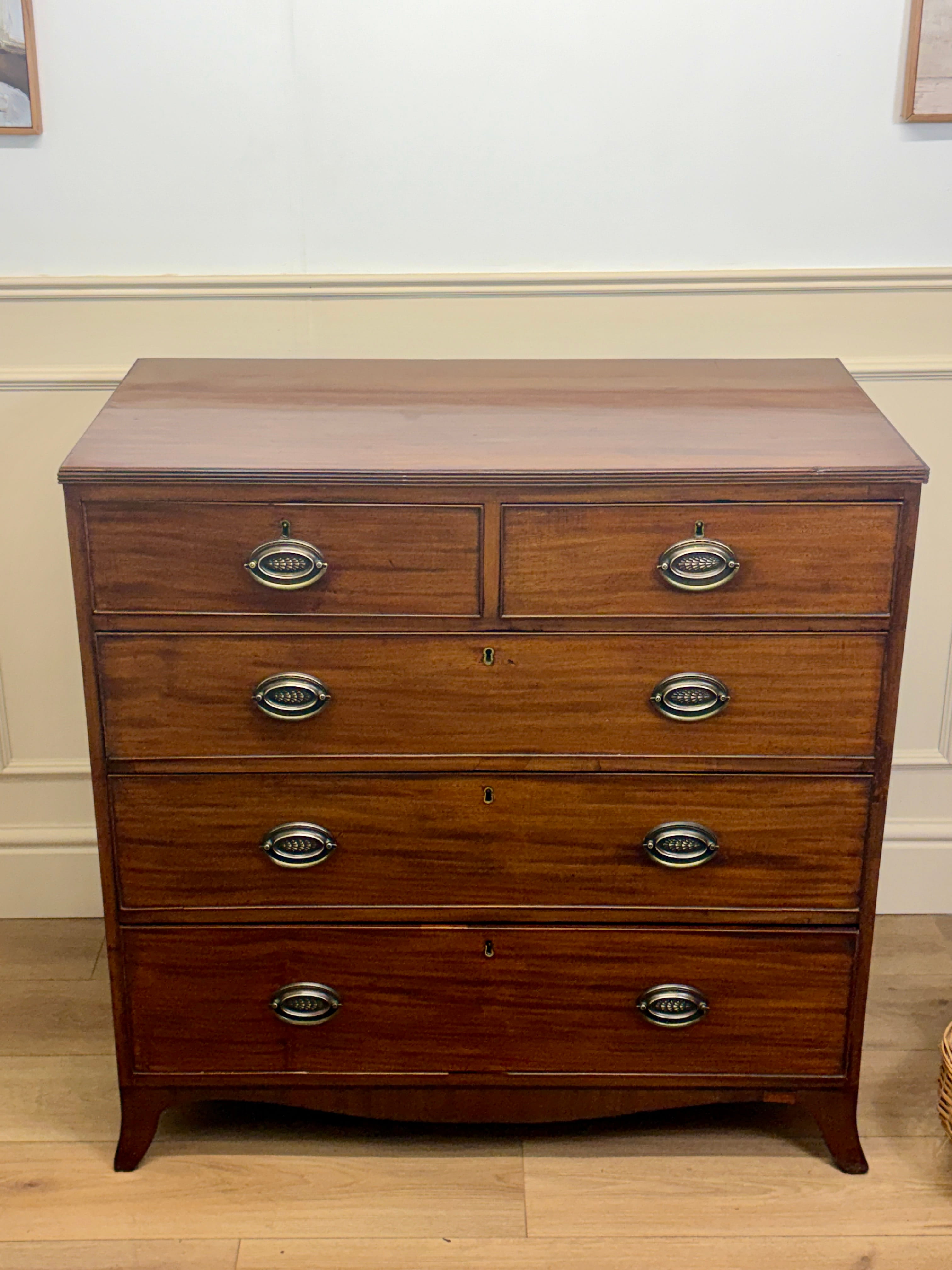 Wooden dresser with four drawers on a wooden floor.