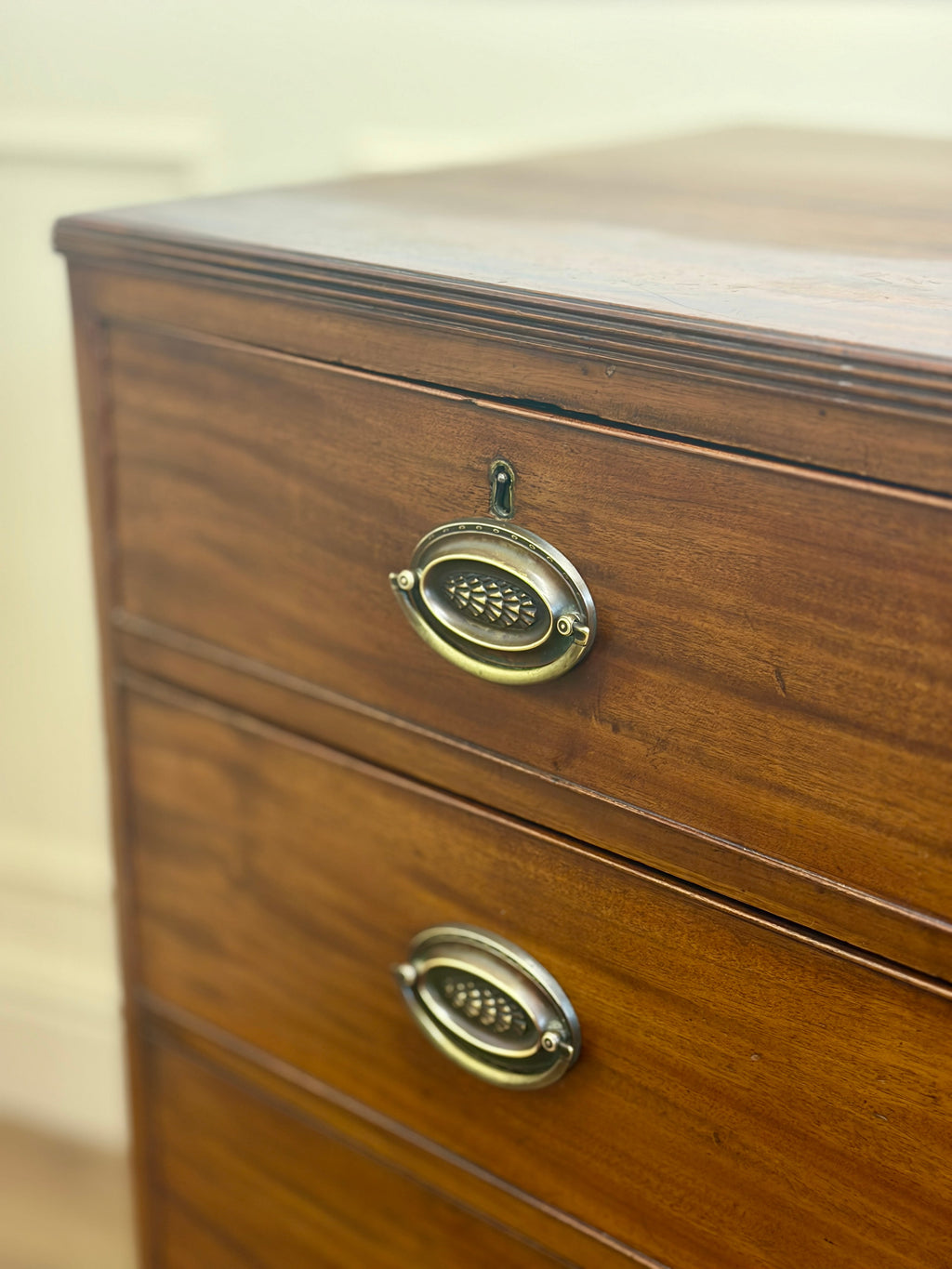 Wooden dresser with brass handles on a plain background