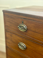 Wooden dresser with brass handles on a plain background