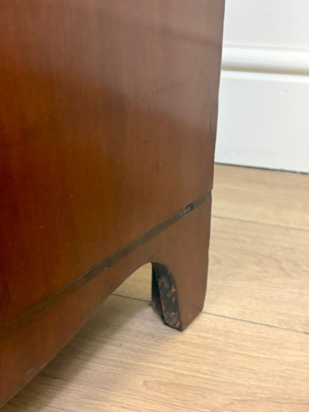 Brown wooden cabinet with a small hole on a wooden floor