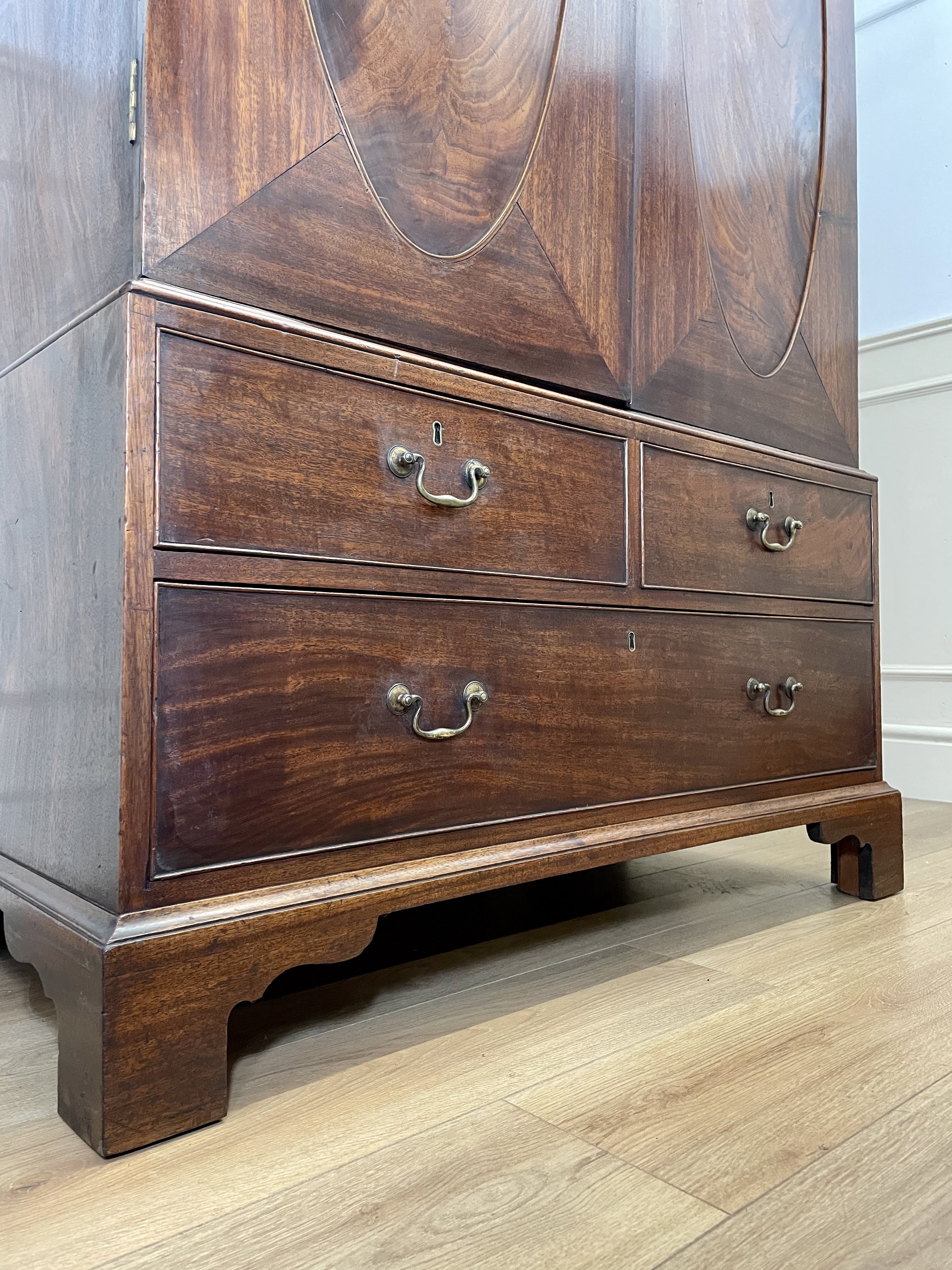 Antique Georgian mahogany tall slim wardrobe with drawers and oval panel doors on ogee bracket feet