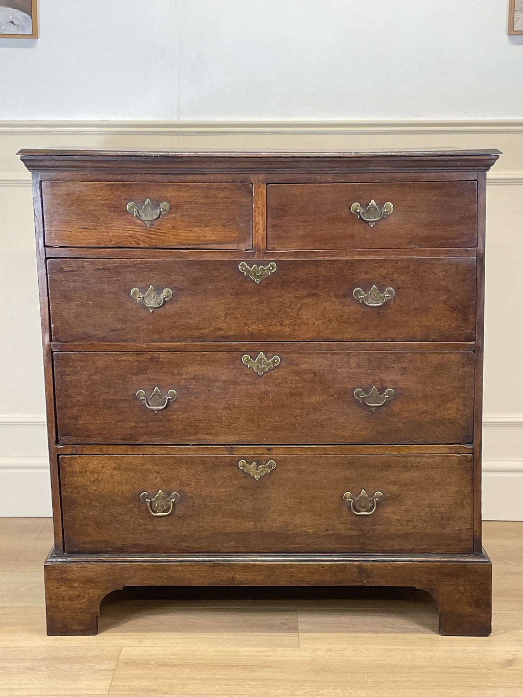 Mid-18th century antique Georgian oak chest of drawers with caddy moulded top, two short and three long graduated drawers, original brass handles, and bracket feet.