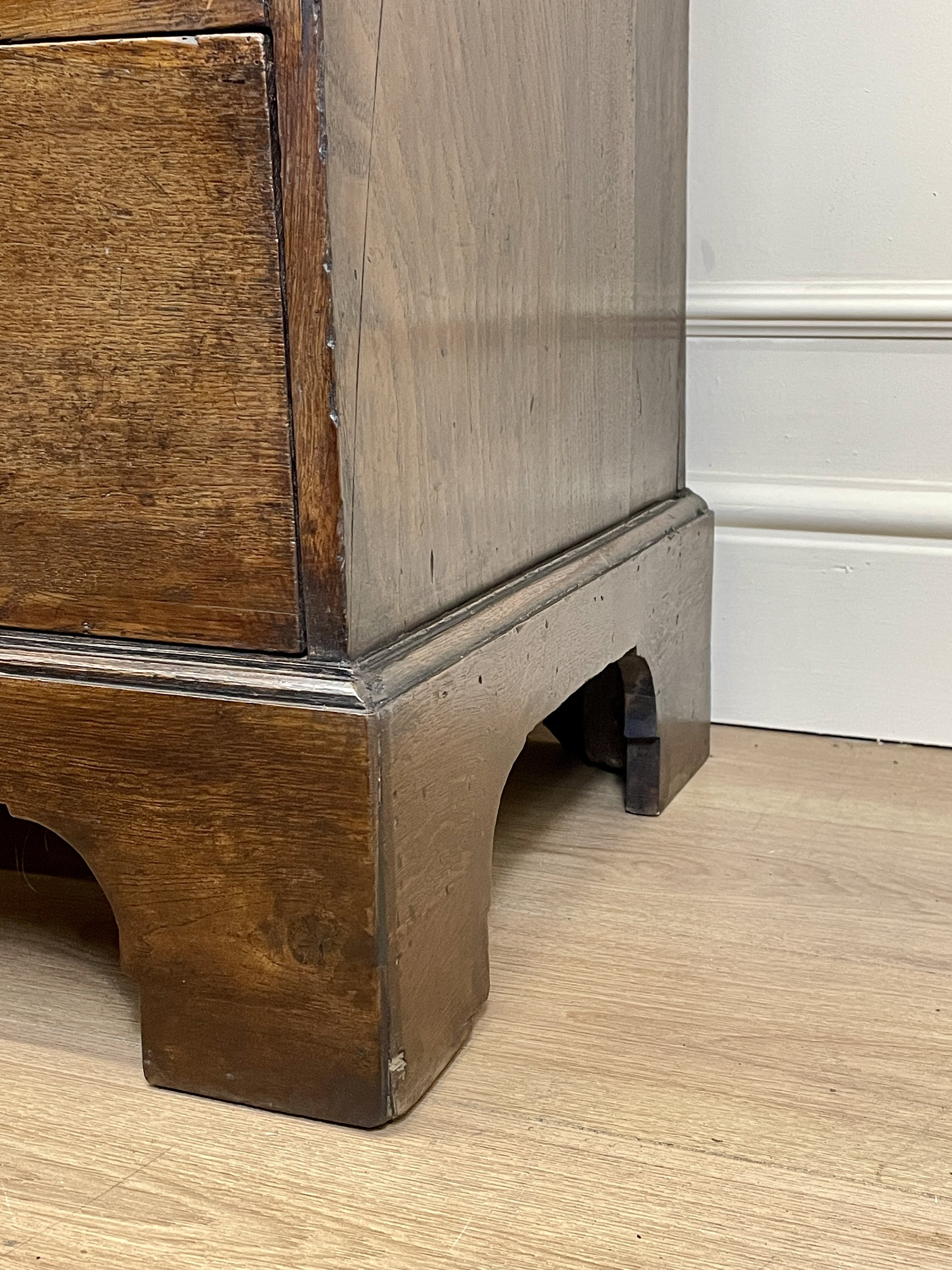 Mid-18th century antique Georgian oak chest of drawers with caddy moulded top, two short and three long graduated drawers, original brass handles, and bracket feet.