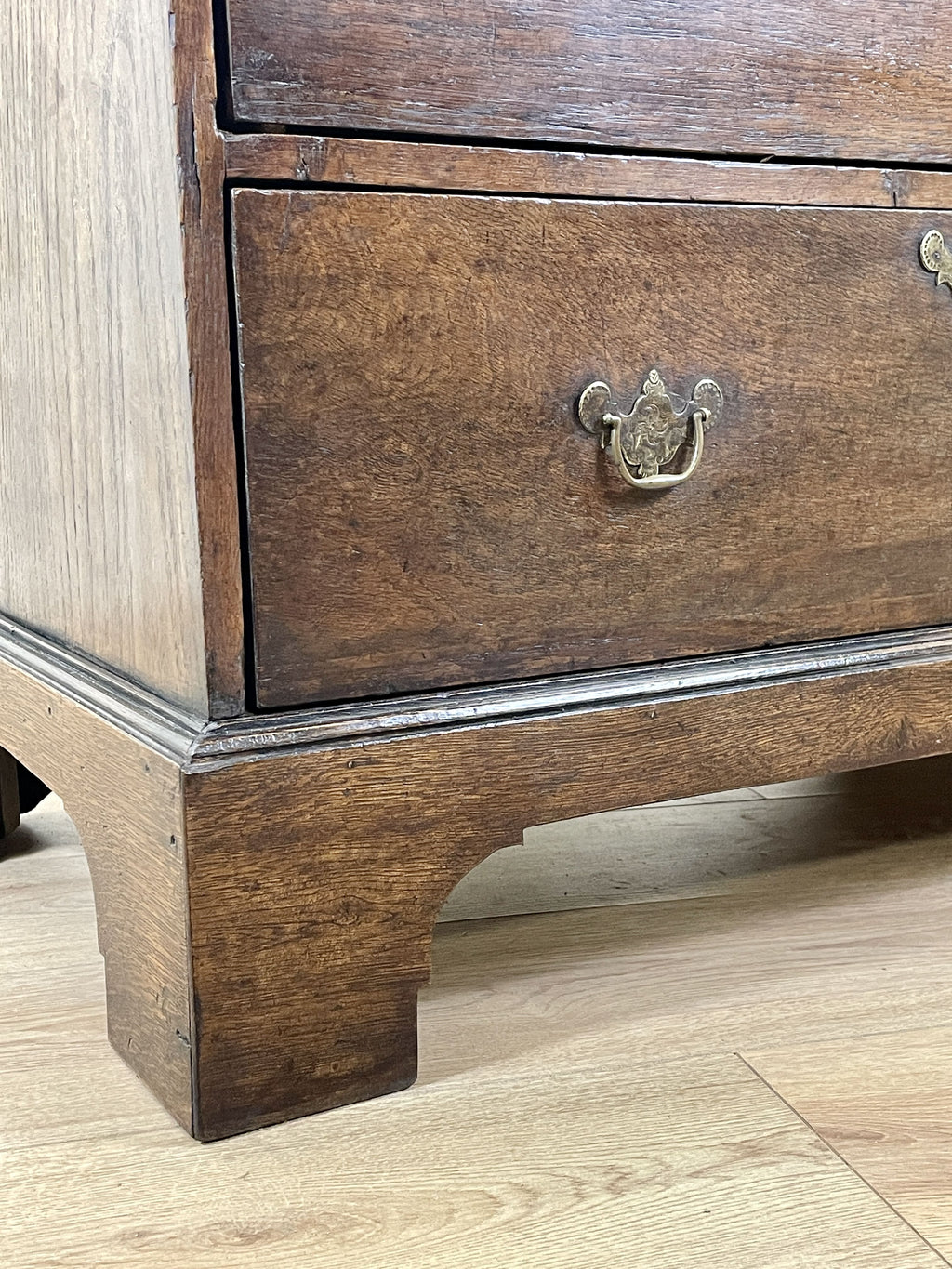 Mid-18th century antique Georgian oak chest of drawers with caddy moulded top, two short and three long graduated drawers, original brass handles, and bracket feet.